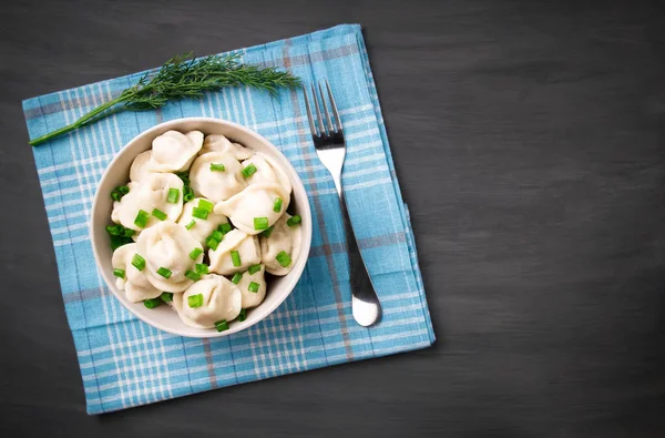 Meat dumplings - Russian dumplings, dumplings with meat on a plate on a black background