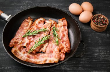 Siyah arka planda biberiyeli kızarmış domuz pastırması, nefis..