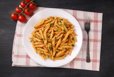 Domates soslu makarna, siyah arka planda maydanozla süslenmiş, çok lezzetli..