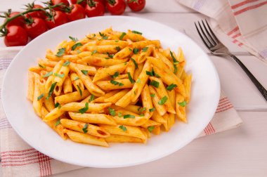 Beyaz ahşap bir masada maydanozla süslenmiş domates soslu makarna, çok lezzetli..