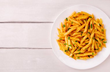 Beyaz ahşap bir masada maydanozla süslenmiş domates soslu makarna, çok lezzetli..