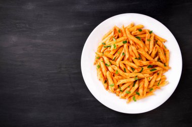 Domates soslu makarna, siyah arka planda maydanozla süslenmiş, çok lezzetli..