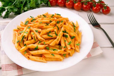 Beyaz ahşap bir masada maydanozla süslenmiş domates soslu makarna, çok lezzetli..