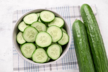 Bahar yeşili sebze salatası için beyaz arka planda bir kasede bir sürü taze salatalık..