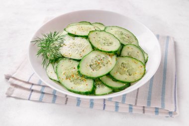 Beyaz arka planda baharatlar olan bir kasede salatalık salatası.