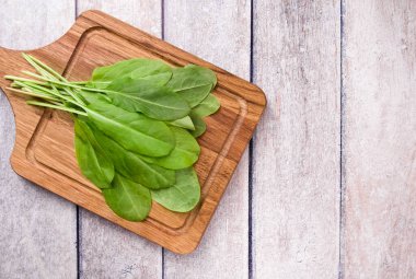 Bahar yeşili sebze çorbası ve salata için ahşap masadaki taze organik kuş sürüsü. Bahar yeşili sebzeler - doru ıspanak