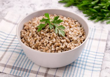 Gri arka planda bir tabakta taze pişmiş karabuğday lapası. Sağlıklı yiyecekler. Vejetaryen yemeği..