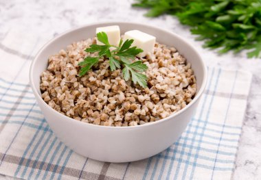 Gri arka planda bir tabakta taze pişmiş karabuğday lapası. Sağlıklı yiyecekler. Vejetaryen yemeği..