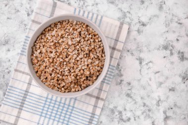 Gri arka planda bir tabakta taze pişmiş karabuğday lapası. Sağlıklı yiyecekler. Vejetaryen yemeği..