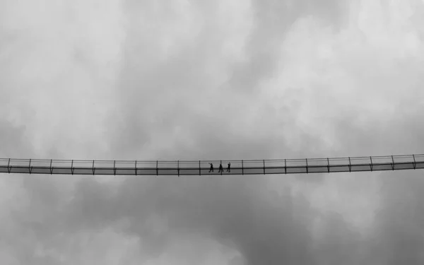 Retrato Branco Preto Pessoas Uma Ponte Suspensão Alta Céu Nublado — Fotografia de Stock