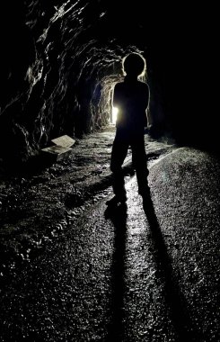 Annesiyle birlikte dağdaki karanlık mağarada bir çocuk.