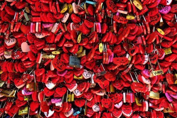 red locks in the shape of hearts on a fence at the balcony of romeo and juliet in verona