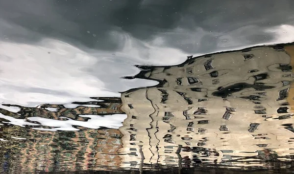 Edifícios que refletem na água na chuva nuvens escuras — Fotografia de Stock