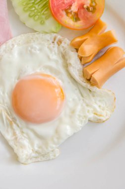 Kızarmış yumurta ve sosis beyaz bir plaka üzerinde