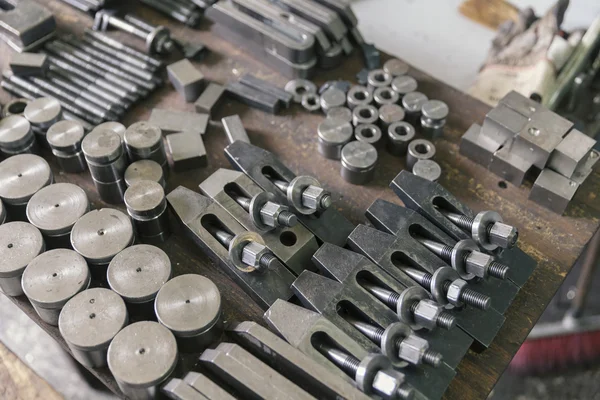 Workin table with metal parts and tool — Stock Photo, Image