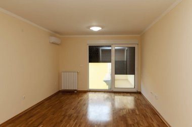 İki penceresi ve parkesi olan boş bir oda