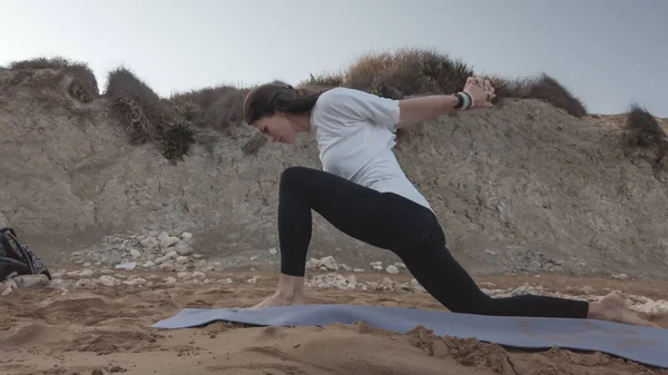 Joven morena caucásica haciendo youga en la playa de arena en la mañana Imagen De Stock