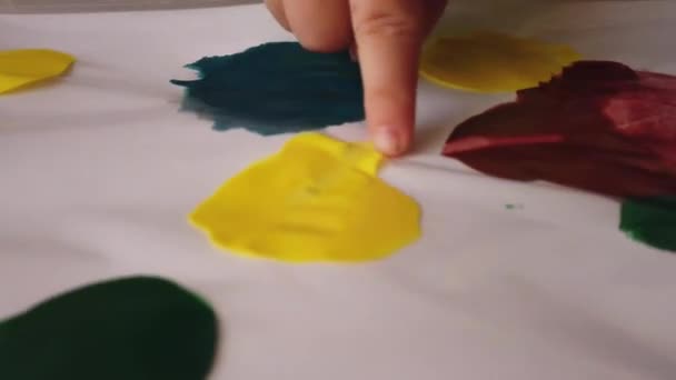 어린이 공예. 천연색으로 칠 해진 플라스틱 폴더 위에 손가락으로 그림을 그리는 어린이 — 비디오