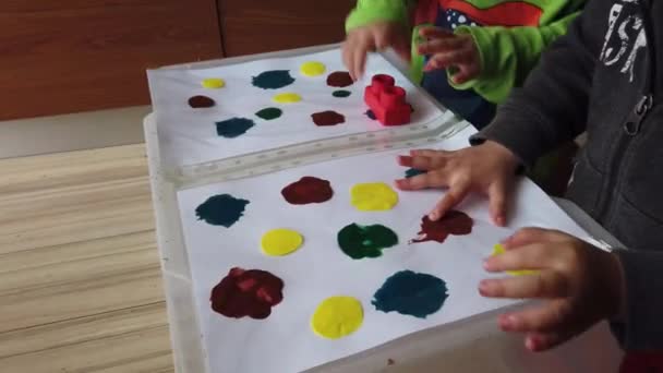 Дитячі ремесла. Діти малюють пальцем над пластиковою папкою, поданою кольорами. Сенсорна активність — стокове відео