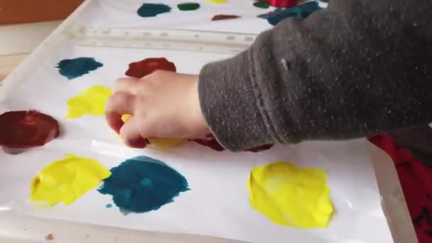 Kids crafts. Child painting with finger over plastic folder filed with colors — Stock Video