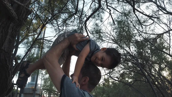 Padre e hijo jugando en el parque. Papá ayudando a un niño a bajar del árbol —  Fotos de Stock