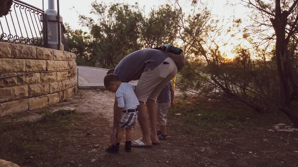 Papa avec deux fils, vérifiant le genou blessé de son bébé garçon — Photo