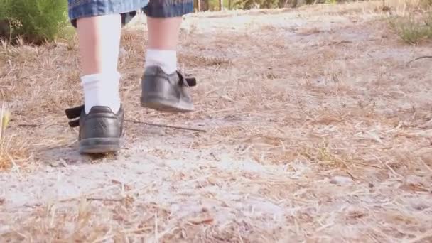 Child walking in the park on dry dusty terrain and falling down. Low angle close up shot — Αρχείο Βίντεο