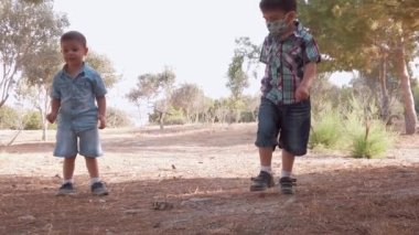 Kardeşler doğada oynuyor. Güneşli yaz gününde kirli ve kuru çimenleri keşfederek kayaları fırlatıyor.