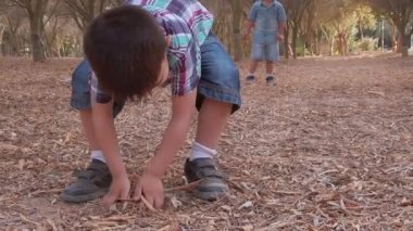 Parka kuru yapraklar atan sevimli kardeşler. Kardeşler doğada eğleniyor.