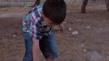 Parkta tahta bir sopayla yere saçılmış küçük bir çocuk.