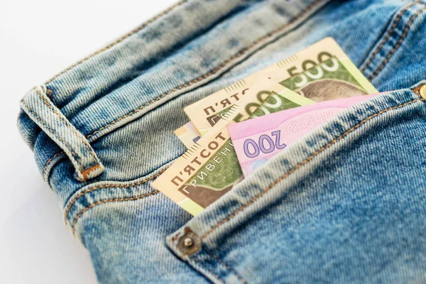 Money in back blue jeans pocket. Denim texture background. Ukrainian five and two hundred hryvnia. National banknotes. Finance, economy and fashion concept.