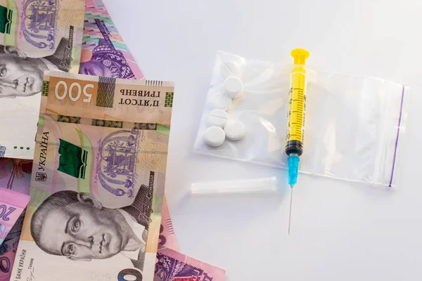 Şırınga, plastik poşette haplar ve Ukrayna parası. Uyuşturucu, kokain, eroin ya da ecstasy satışı. Yasadışı iş. Sağlık ve Tıp Konsepti.