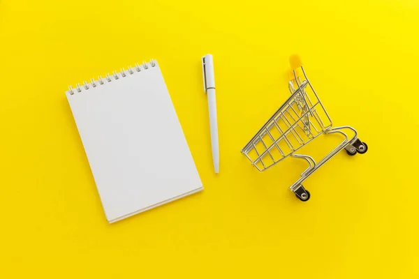 Blank Notatnik Długopis Mini Wózek Supermarketu Żółtym Tle Zakupy Online — Zdjęcie stockowe