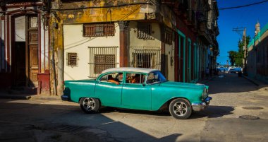 Havana, Küba, Temmuz 2019, şehrin en eski kesişme noktasında yolcuların geçtiği yeşil, eski klasik bir Chevrolet araba manzarası.