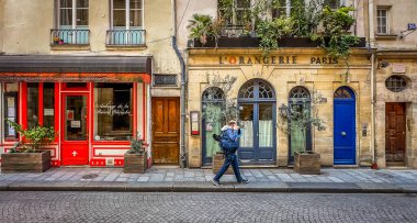 Paris, France, March 25th, 2025, view of a man walking by some restaurants on Saint-Louis en l'ile Street in the 4th district of the capital