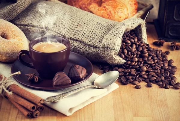 Cup hot coffee with beans and chocolate candies — Stock Photo, Image