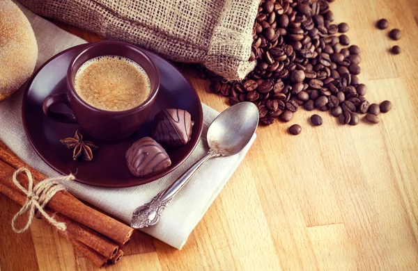 Cup hot coffee with beans and chocolate candies — Stock Photo, Image