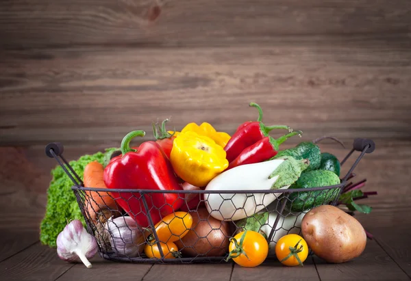 Fresh vegetables in basket on wooden board — Stock Photo, Image