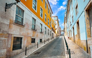 Architectural details in Lisbon, capital of Portugal. Windows on walls of building along sloping street with paving stones. Sunny day.