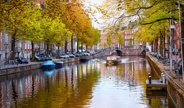 Amsterdam, Hollanda. Hollanda 'nın sonbahar panoramik manzarası. Ünlü kanal Amstel River turistik eğlence teknesi. Akşam manzarası. Renkli günbatımı sahnesi. Avrupa 'nın ünlü tatil beldesi.