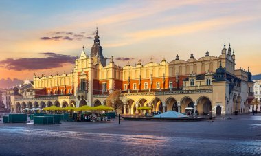 Krakow, Polonya. Eski kasabanın pazar meydanı. Kule ve kulede saat var. Günbatımı panoraması. Sıcak güneş ışığı ve kaldırım taşlarının yansımaları. Doğu Avrupa seyahati