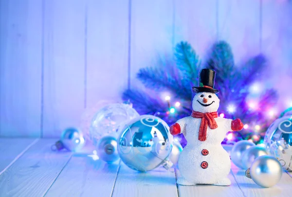 Muñeco de nieve de Navidad con bolas y guirnaldas en tablero de madera — Foto de Stock