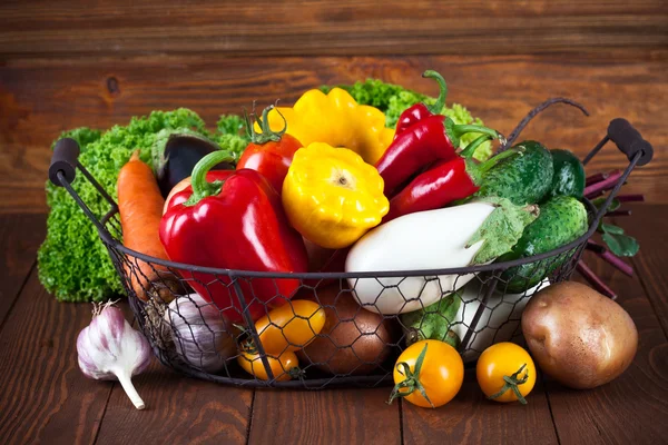 Fresh vegetables in basket on wooden board — Stock Photo, Image