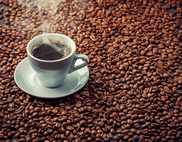 Bebida café aromática caliente en la taza blanca con granos de fondo —  Fotos de Stock