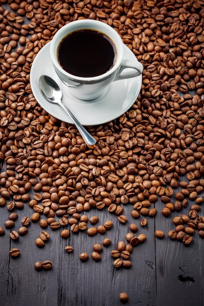 Tasse mit duftendem Kaffee trinken auf Bohnen-Hintergrund — Stockfoto