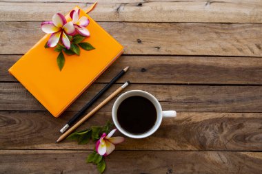 Sıcak kahve ve çiçeklerle iş yapmak için dizüstü bilgisayar planlayıcısı. Frangipani düzenleme düz zemin üzerinde yatıyordu. Ahşap.
