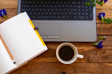 Not defteri planlayıcısı, iş için bilgisayar sıcak kahve, mavi çiçekler kelebek bezelye düzenleme düz zemin üzerinde yatıyordu ahşap