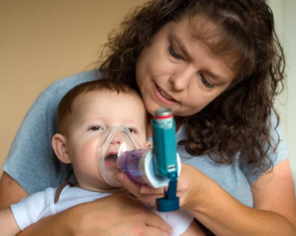 Infant getting breathing treatment from mother while suffering f Stock Image