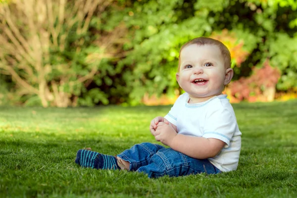 Usmívající se šťastné dítě hraje venku v trávě — Stock fotografie