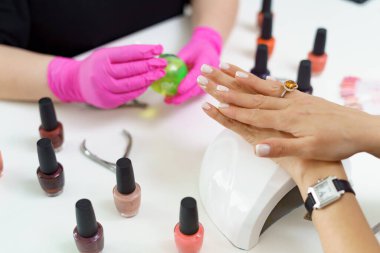 Güzellik salonunda manikürcü müşteriyi tedavi ediyor. Manikür, çivi boyası.